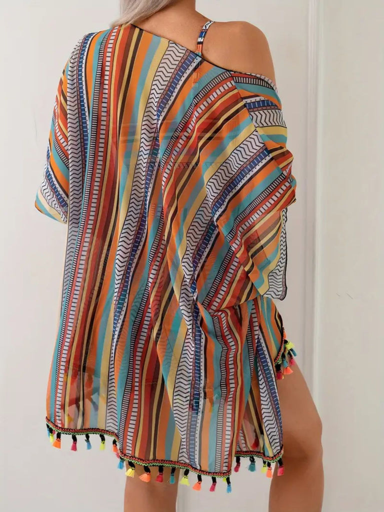 Multicolored striped dress with tassels on a plain background