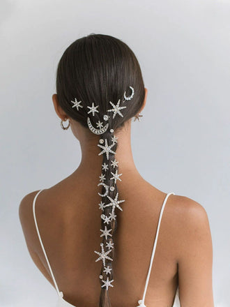 Woman with intricately styled hair featuring starfish and moon designs on a plain background