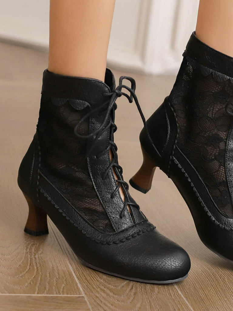 Black lace-up shoes worn by a person on a wooden floor.