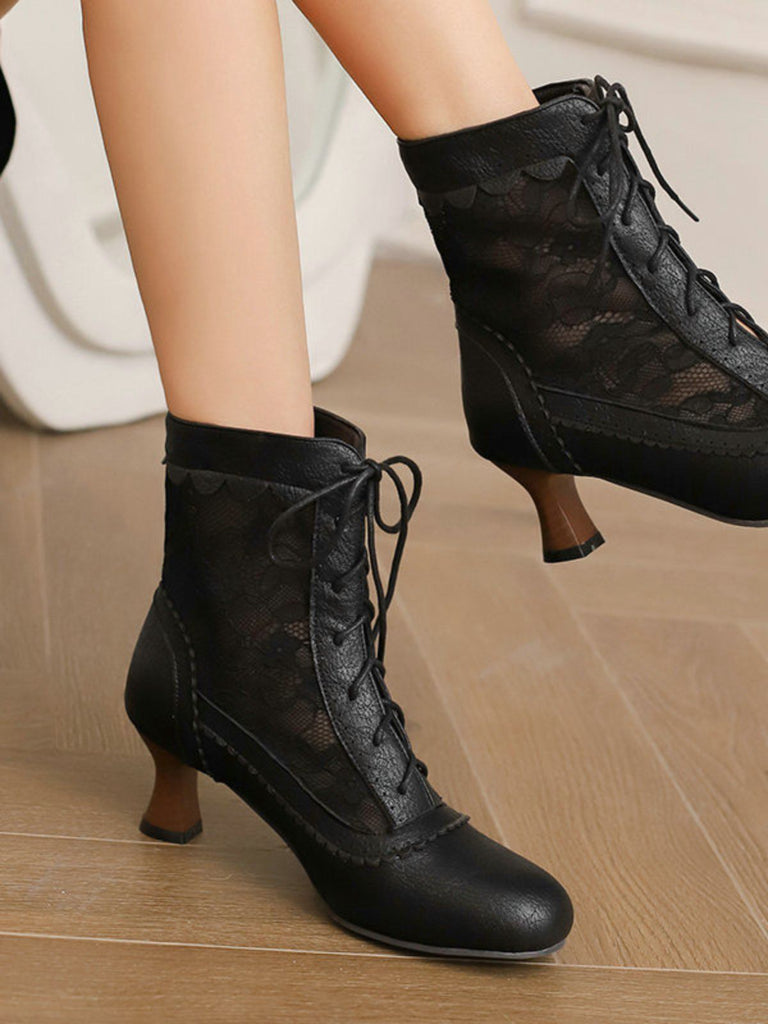 Black lace-up high-heeled boots on a wooden floor.