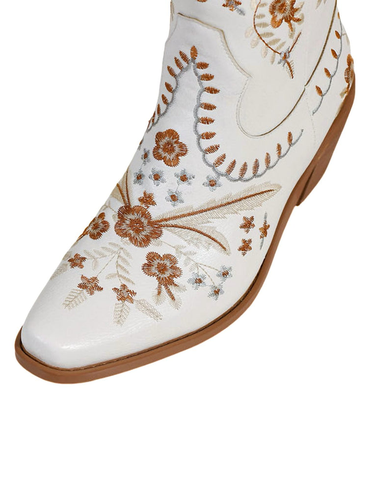 White shoe with brown floral embroidery on a white background