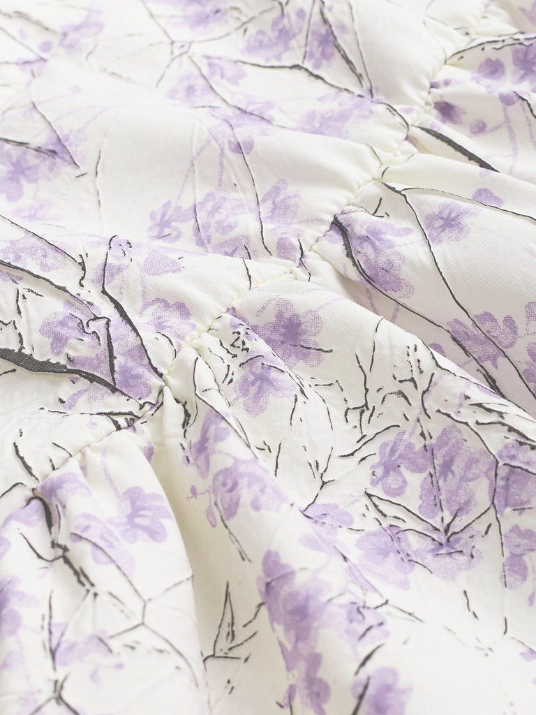 Close-up of fabric with purple floral pattern on white background