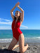She's wearing Red 1930s Retro Halter Solid One-piece Swimsuit and the whole beach remembers the 1930s