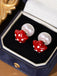 Pair of earrings with red mushroom design and pearl-like elements in a jewelry box.