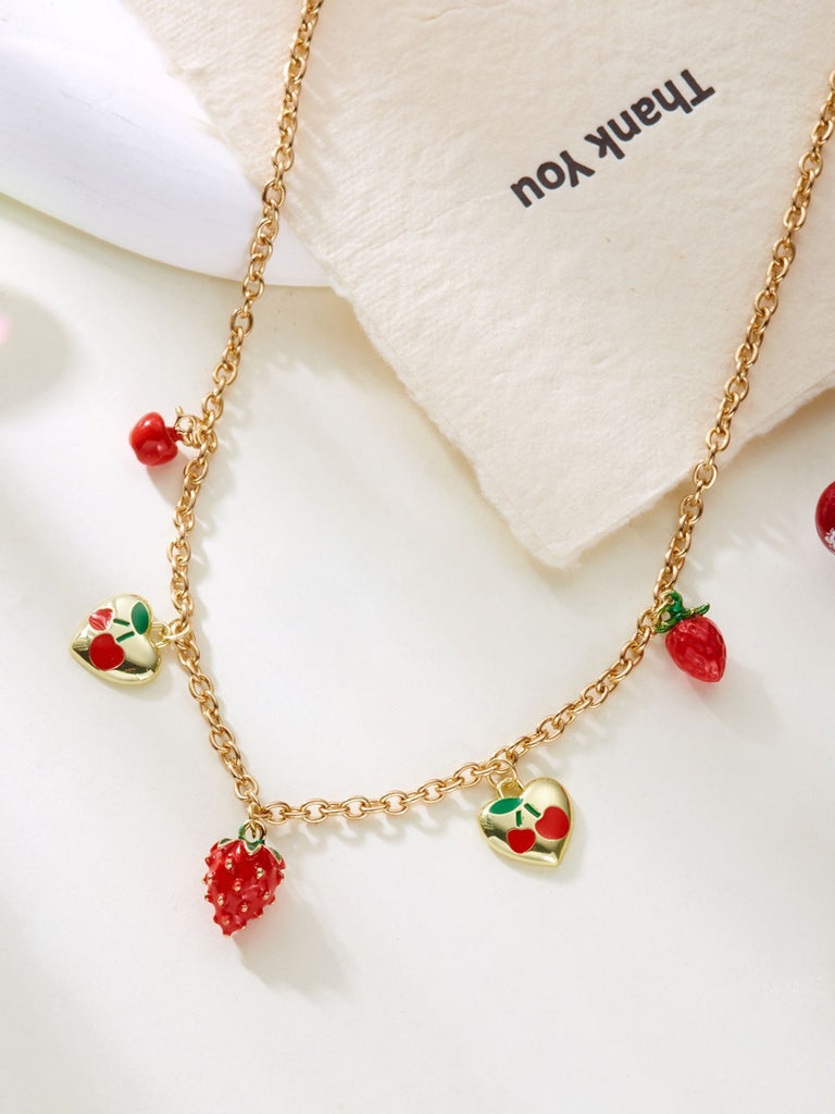 Gold necklace with strawberry-shaped pendants on a white background
