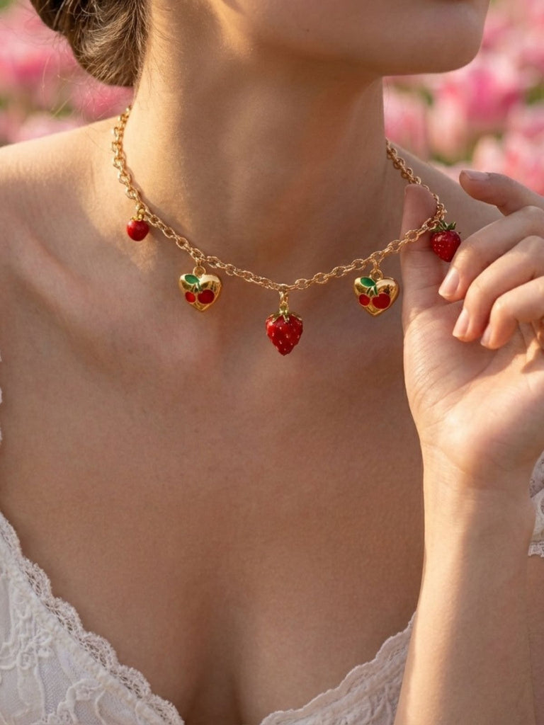 Necklace with strawberry charms worn by a person in a blurred pink floral background