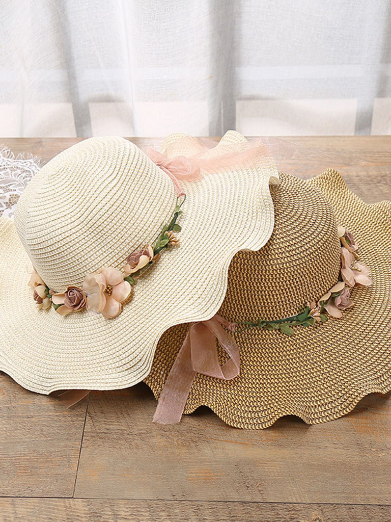 Two straw hats with floral decorations on a wooden surface.