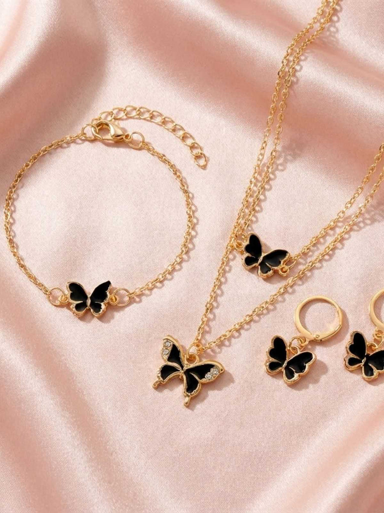 Gold jewelry set with butterfly pendants on a pink satin background