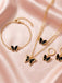 Gold jewelry set with butterfly pendants on a pink satin background