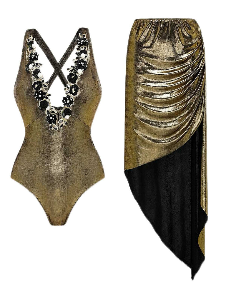Front view of the metallic gold swimsuit paired with a matching draped sarong featuring black fringe detail.