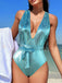 A model wearing the metallic teal snake-print swimsuit on a beach, showcasing the fit and vibrant color in natural sunlight.
