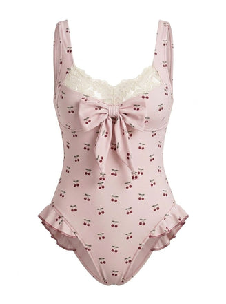 A dusty pink one-piece swimsuit featuring an all-over cherry print, a cream lace sweetheart neckline, and a decorative front bow.
