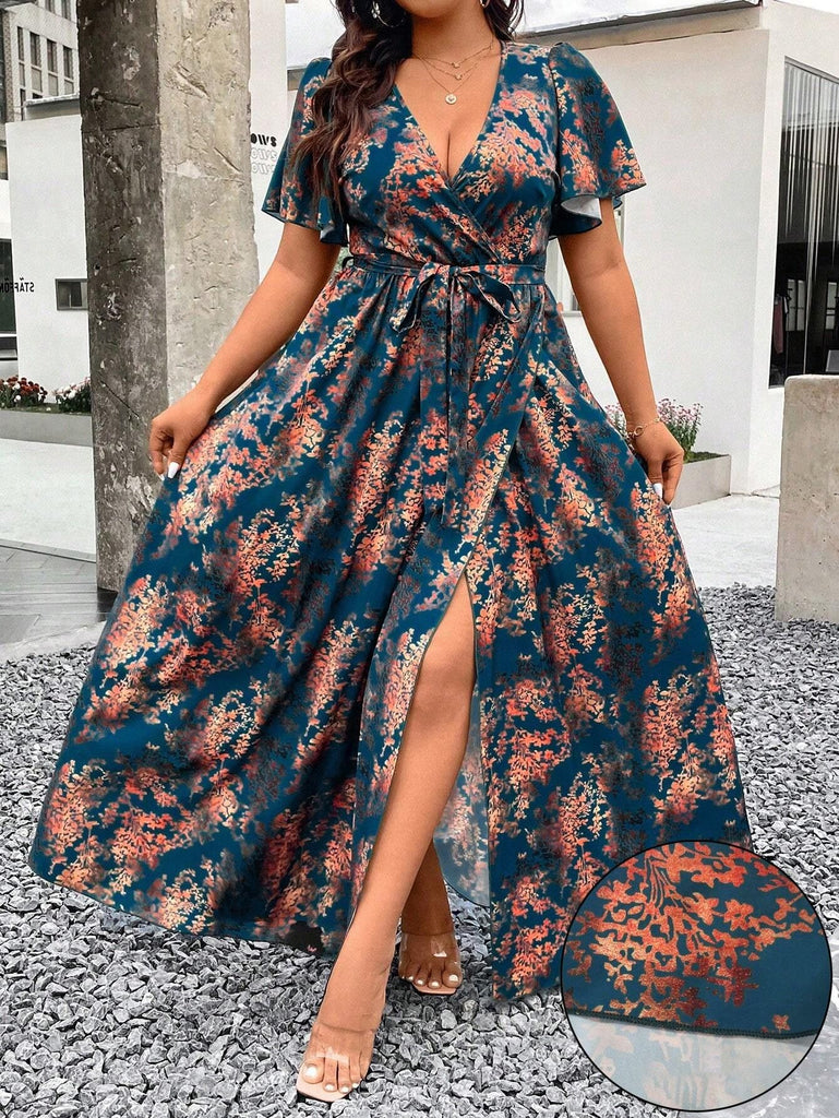 A woman wearing a teal wrap-style maxi dress featuring a rust-colored floral print, a deep V-neckline, flutter sleeves, and a high leg slit.
